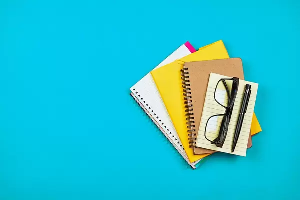 Pile of different notepads and diaries on blue background