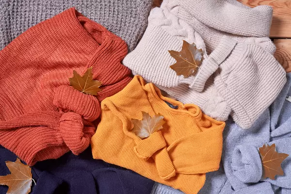 pile of knitted sweaters and fall leaves