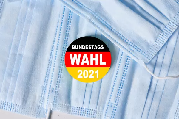 Pile of medical face masks and a pin in German flag. Bundestagswahl 2021