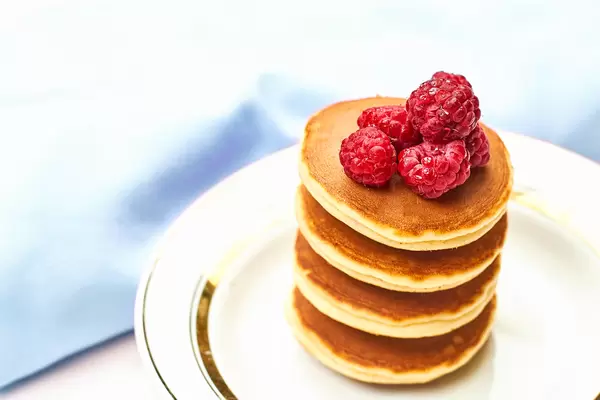 Pile of pancakes with fresh ripe raspberries