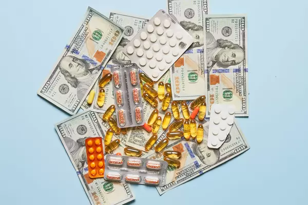 Piles of different medications and us dollars on blue background