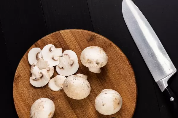 Pilze auf dem Holzbrett mit Messer