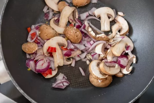 Pilze, Zwiebeln und Chili in einer Pfanne werden angebraten