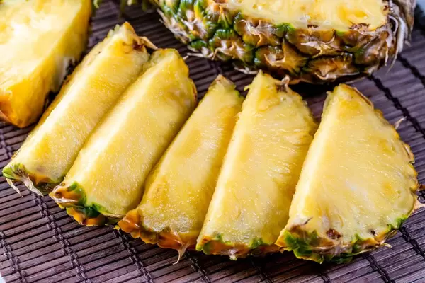 Pineapple cut into pieces on a brown background