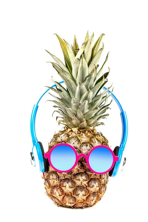Pineapple wearing sunglasses and headphones. Concept of summer vacation, recreation
