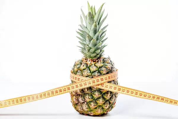 Pineapple with measuring tape on white background. Diet food concept (Flip 2019)