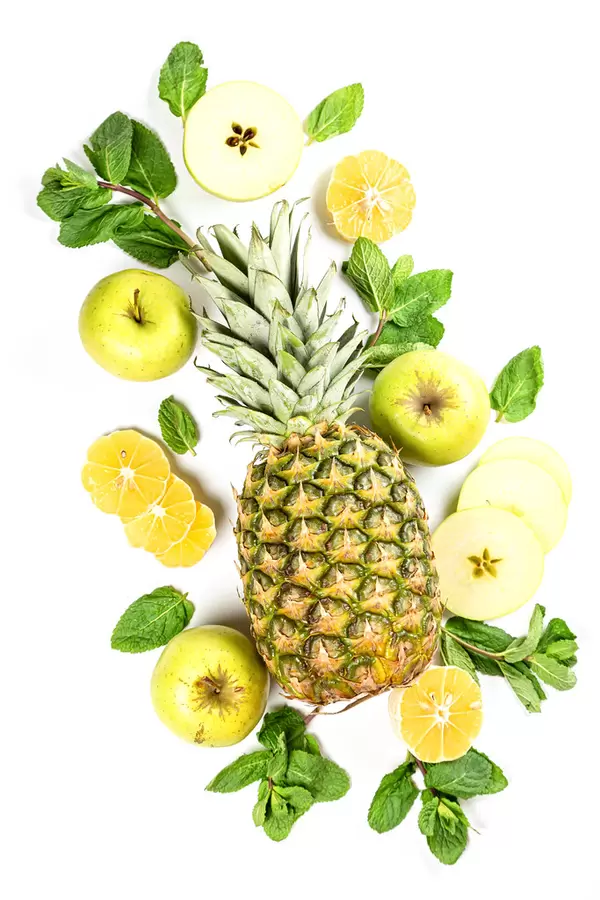 Pineapple with mint leaves, sliced apples and lemon, top view