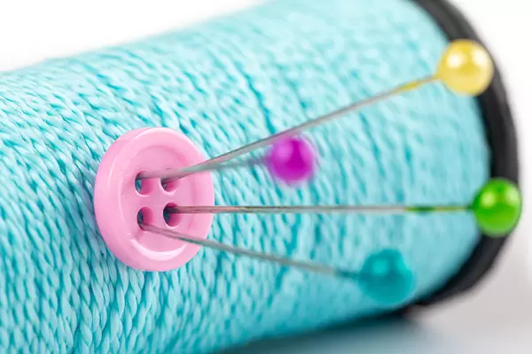 Pink button pinned to a spool of thread, close-up