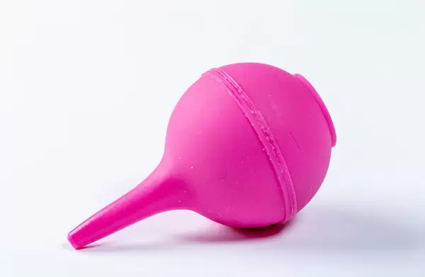Pink enema bulb on white. Medical children's enema