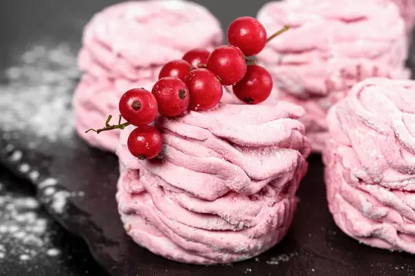 Pink homemade zephyr with red currant berries, close up