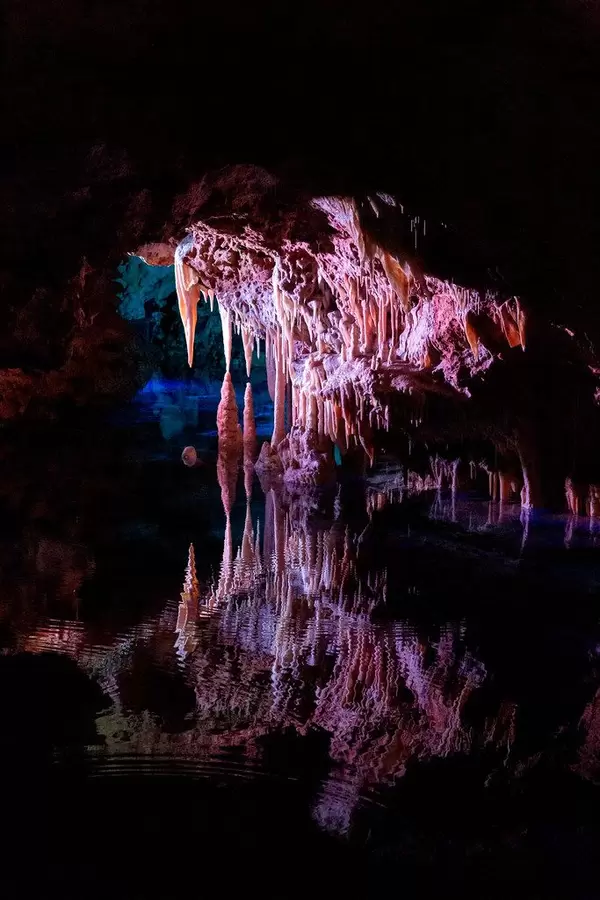 Pink lighting on the stalactites reflecting in the waters of the Sea of Venice, Cuevas del Hams caves