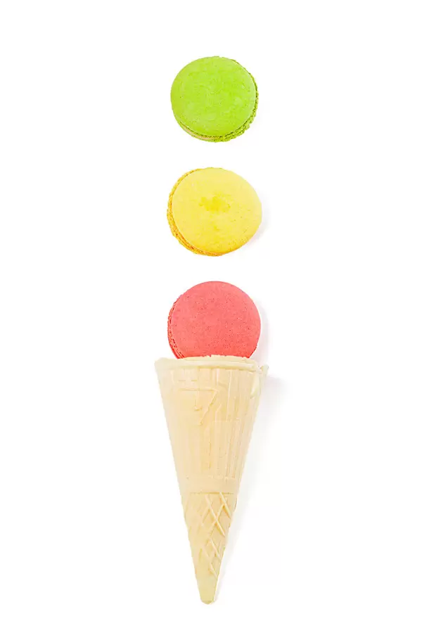 Pink, yellow and green macaroons on white background with waffle cone