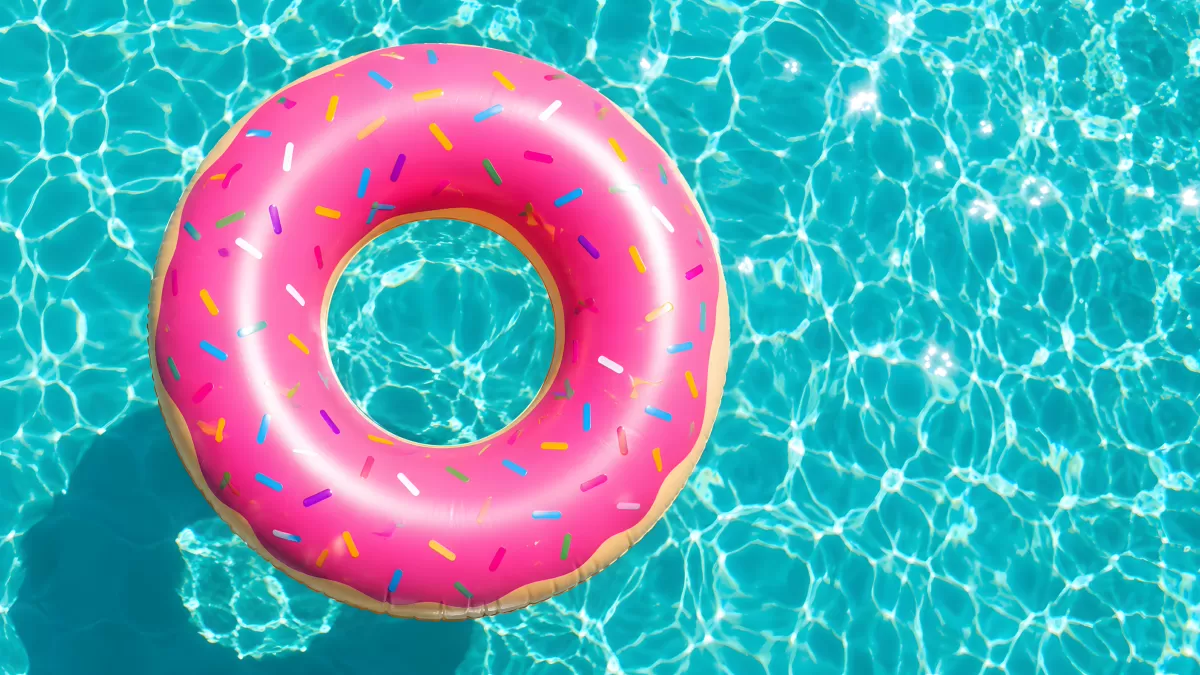 Pinker Donut-Schwimmring treibt im türkisen Pool
