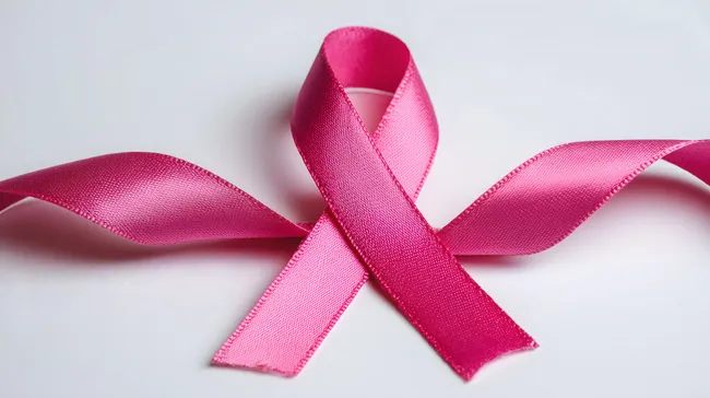 Pinkes Brustkrebs-Bewusstseinsband vor weißem Hintergrund