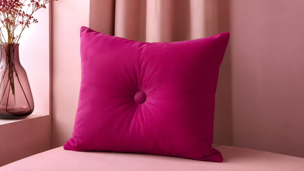 Pinkes Samtkissen mit Knopf auf rosafarbenem Untergrund