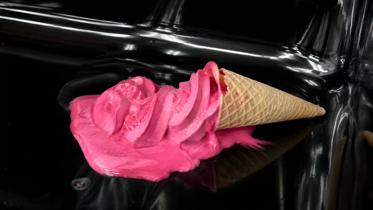 Pinkes Softeis fällt vom Waffeleis auf schwarzes Auto
