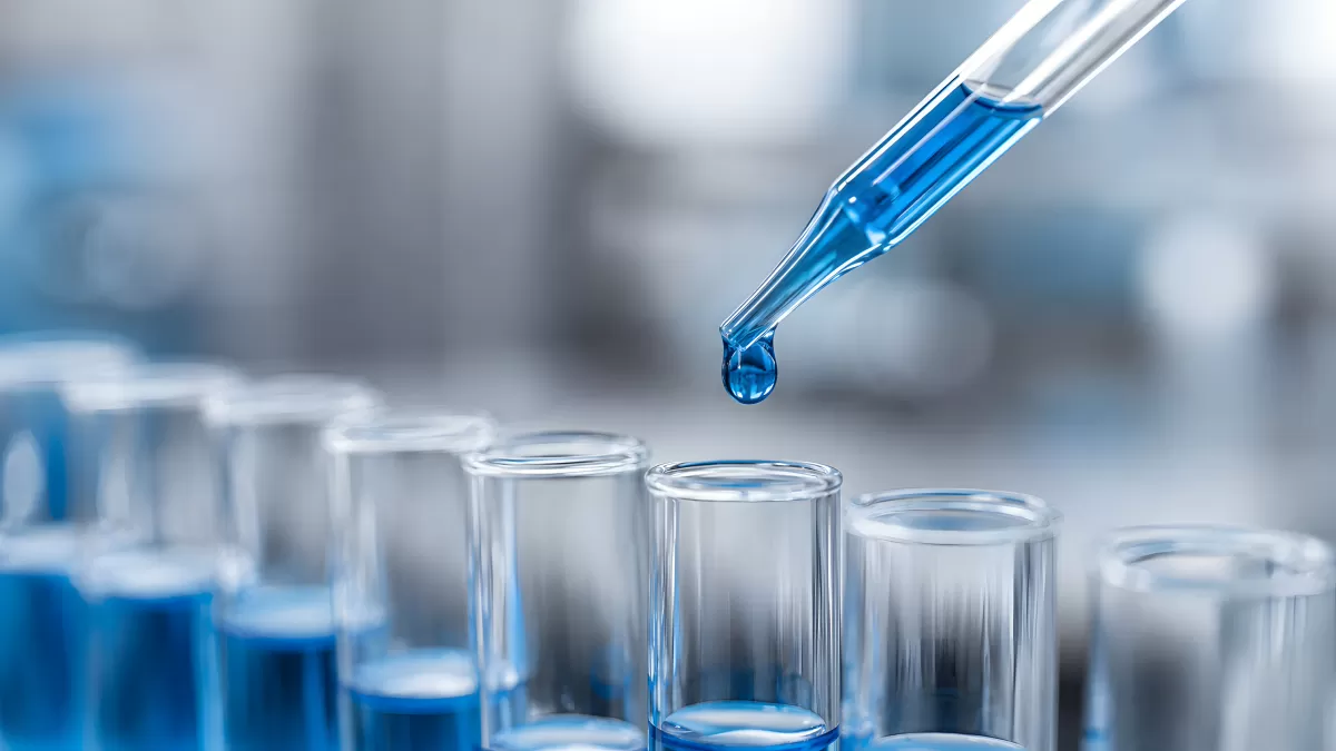 Pipette tropft blaue Flüssigkeit in Reagenzgläser