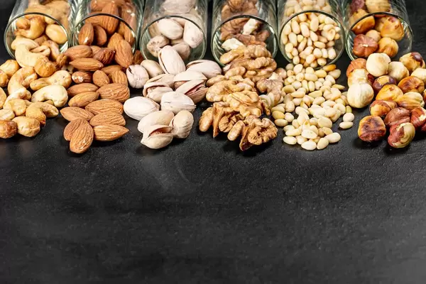 Pistachios, almonds, cashews, walnuts, pine nuts and hazelnuts on a black background (Flip 2020)
