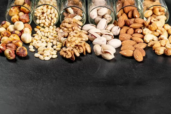 Pistachios, almonds, cashews, walnuts, pine nuts and hazelnuts on a black background