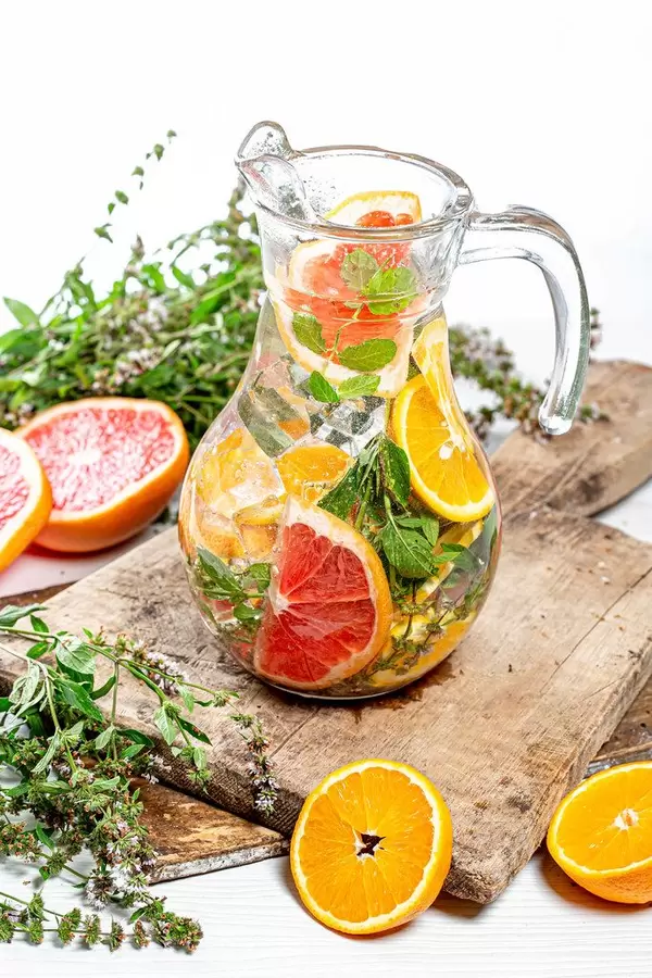 Pitcher of ice cubes, fresh mint, and citrus slices on old kitchen boards