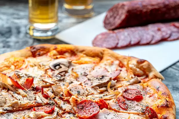 Pizza cold cuts with ham, chicken and smoked sausage on the grey table