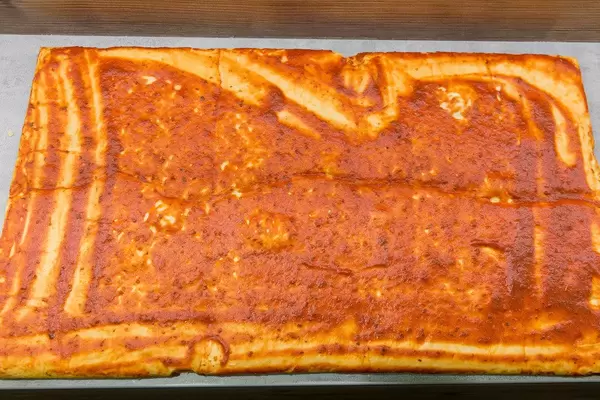 Pizza in der Zubereitung - Ausgerollter Teig mit Tomatensauce