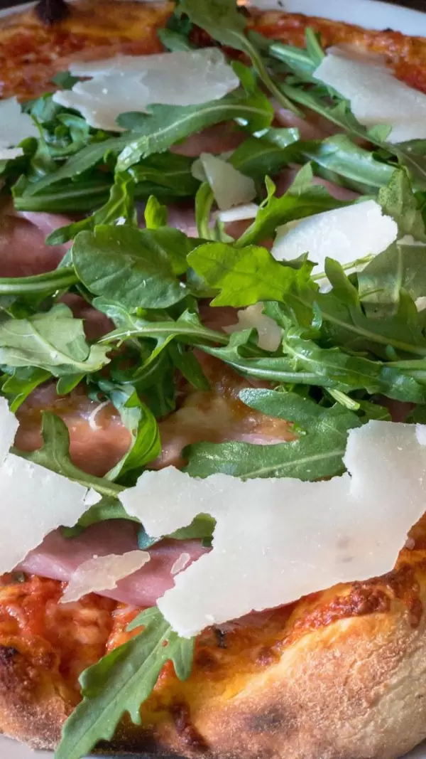 Pizza mit Parmaschinken, Rucola und Parmesan