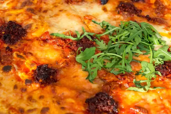 Pizza NDUJA CALABRESE in der L'Osteria, mit Mozzarella, italienischer Streichsalami, halbgetrockneten Kirschtomaten und Ruccola