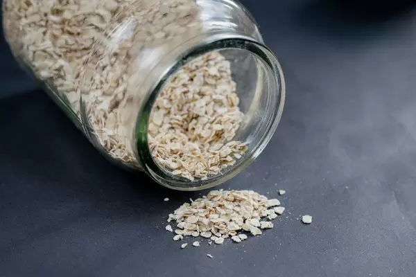 Plain oat flakes in a glass cup on a black background