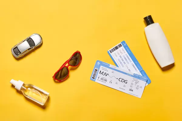 Planning summer vacations - flight tickets, anti-tan cream, hand sanitizer, sunglasses and miniature car model