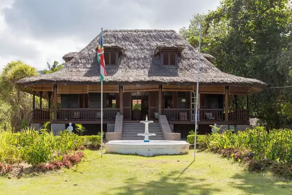 Plantation House National Monument - Sehenswürdigkeit mit Strohdach und weißem Brunnen ist Teil des L'Union Estate auf La Digue