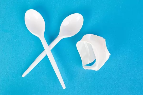 Plastic cup with plastic spoons on blue background
