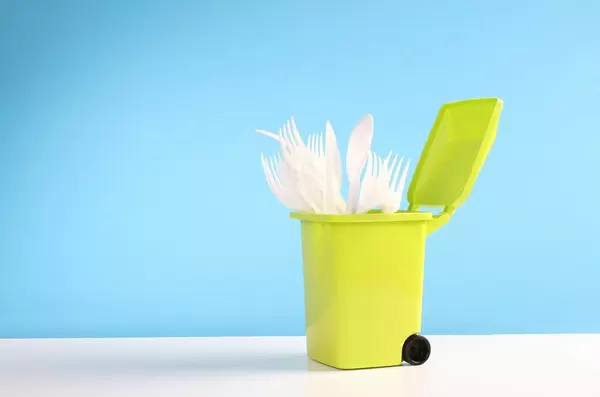 Plastic disposable forks and spoons in a trash can