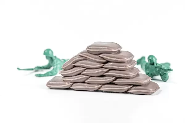 Plastic soldiers lie with arms behind bags on a white background. Protection concept