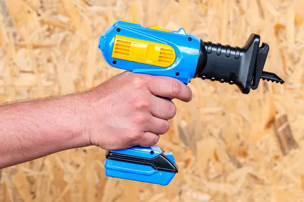 Plastic toy electric saw in the man's hand
