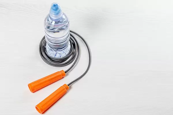 Plastic water bottle with jump rope on white background. The concept of an active lifestyle (Flip 2019)
