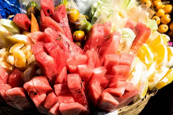 Plastikbeutel mit verschiedenen geschnittenen Früchten wie Wassermelone oder Mandarinen in Korb