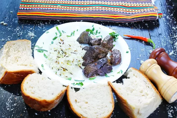 Plate with duck liver and wild rice served with bread. Wooden black table (Flip 2019)