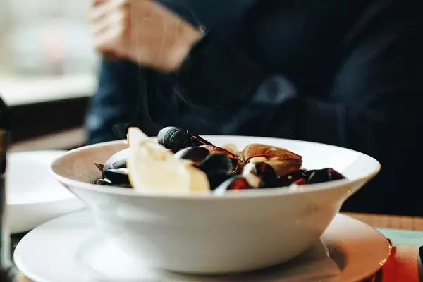 Plate with fresh and hot mussels with lemon. Blurry background.