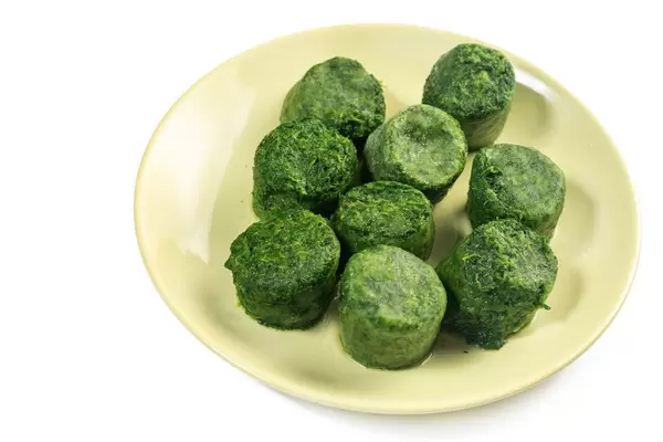 Plate with Frozen cubes of Spinach above white background