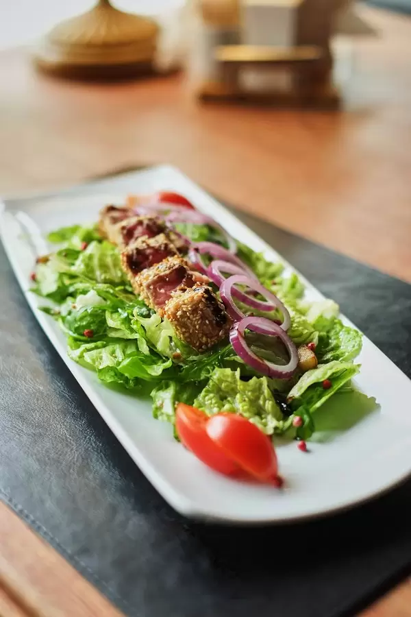 plate with pieces of fried fish and salad on wooden table side view  Flip 2019