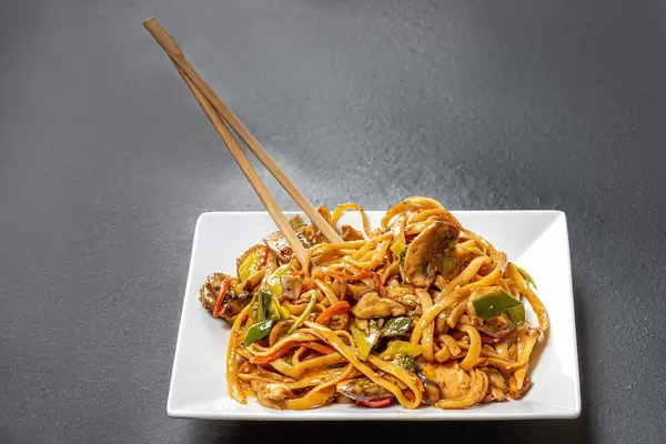 Plate with rice noodles and chopsticks on black background (Flip 2019)