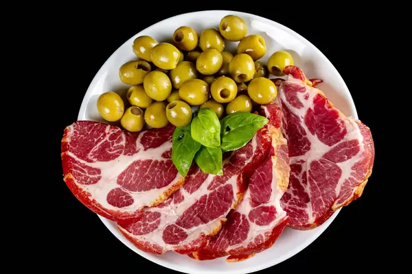 Plate with sliced smoked meat and green olives