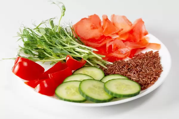 Plate with vegetables, pickled ginger, brown rice and micro-green peas on a white background (Flip 2019)