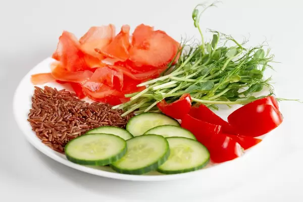 Plate with vegetables, pickled ginger, brown rice and micro-green peas on a white background