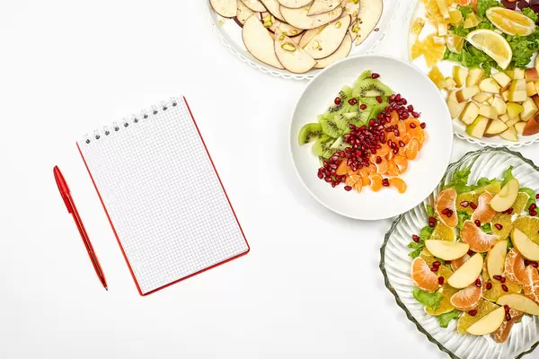 Plates of healthy salads with a blank notepad
