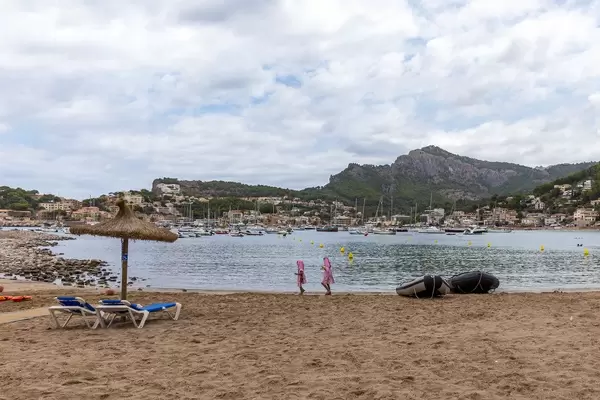 Platja d'en Repic, Soller (Mallorca). Zwei Mädchen mit rosa Bademantel, Sonnenliegen und Sonnenschirm