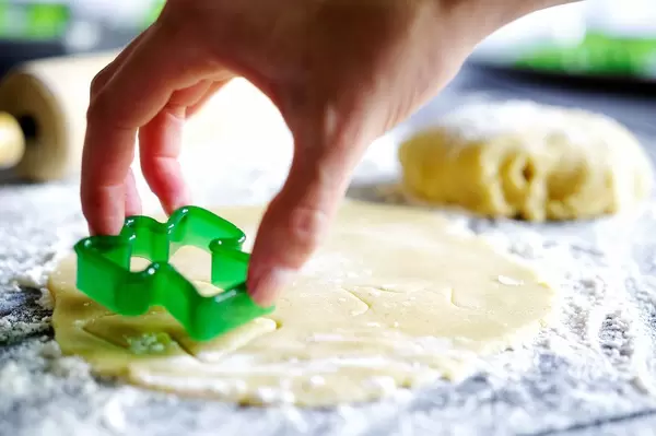 Plätzchen in Engelsform werden in Plätzchenteig gestanzt