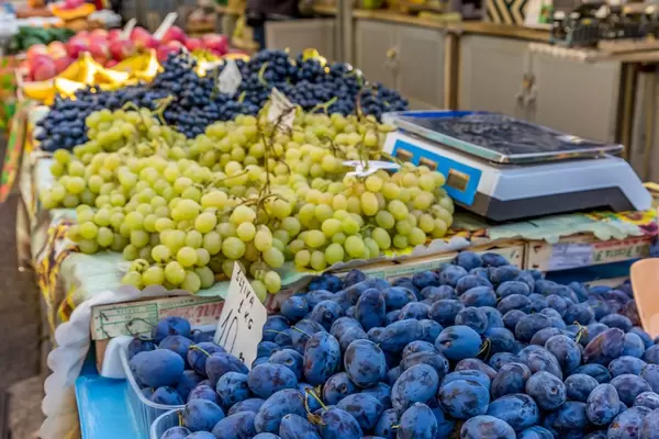 Plums, black and white grapes on marketplace