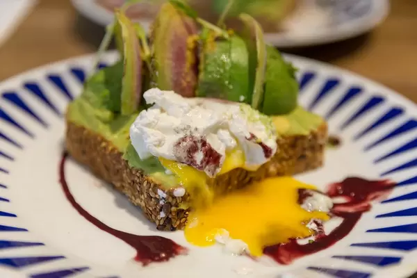 Poacched egg topping on avocado toast with açai and yuzu sauces at Flax&Kale restaurant in Barcelona